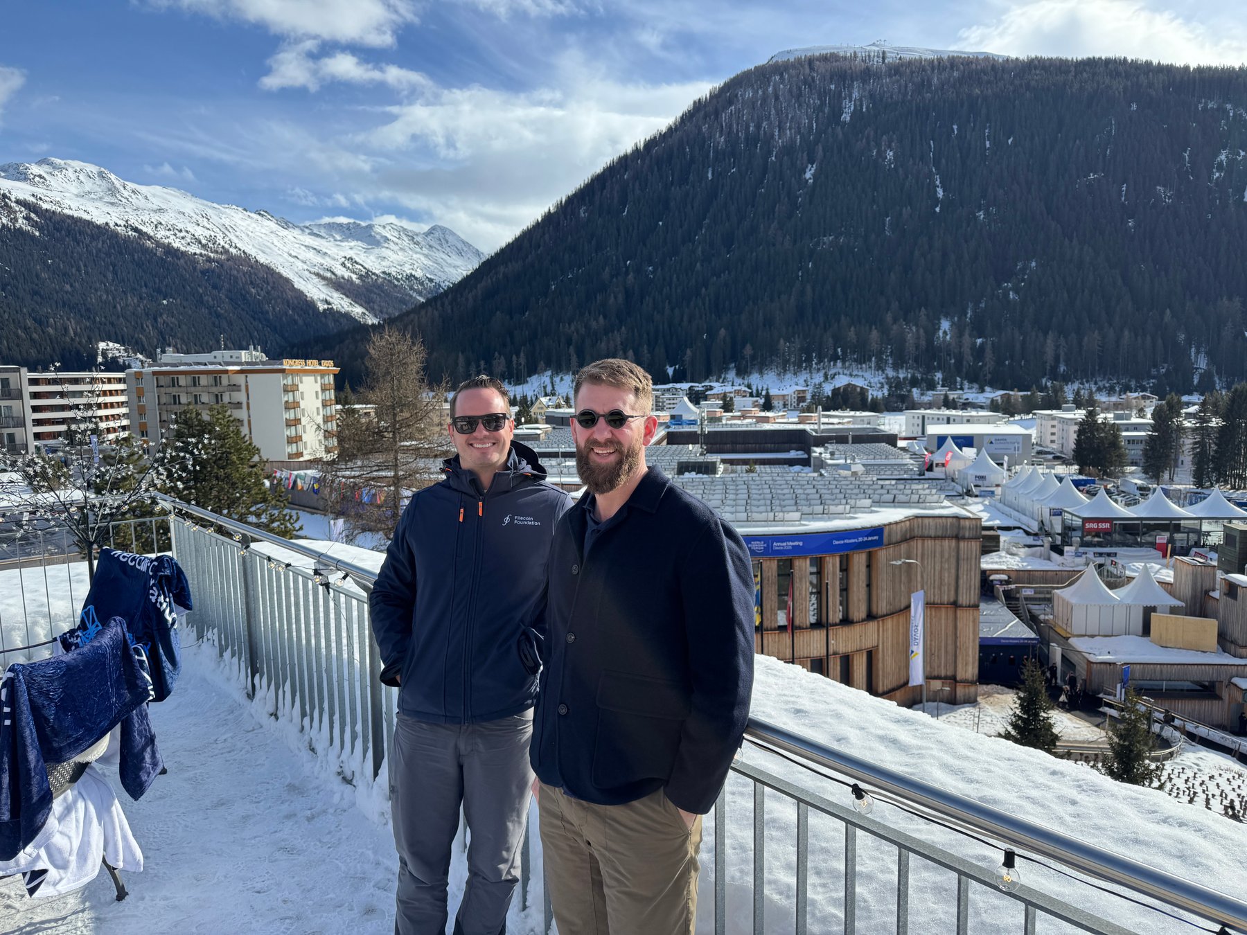 Aaron Stanley with an interview guest on a terrace overlooking the Davos Congress Centre
